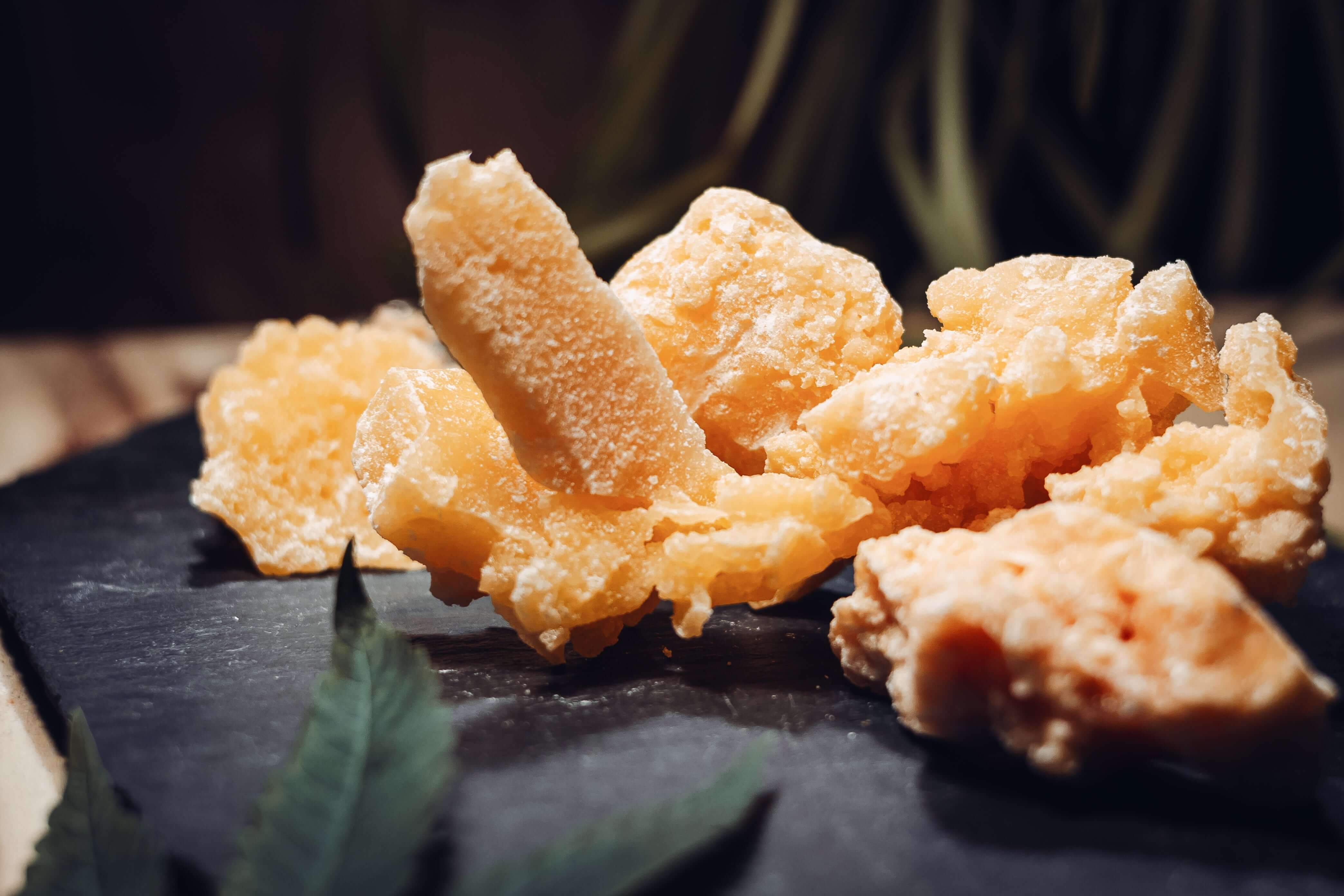 CBD Crumble pieces on a slate board, showcasing the texture and quality of CBD Extrakte. Alle Produkte available.
